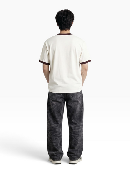 Back view of a man wearing an E7 unisex off-white ringer t-shirt with dark brown trim and relaxed fit jeans.
