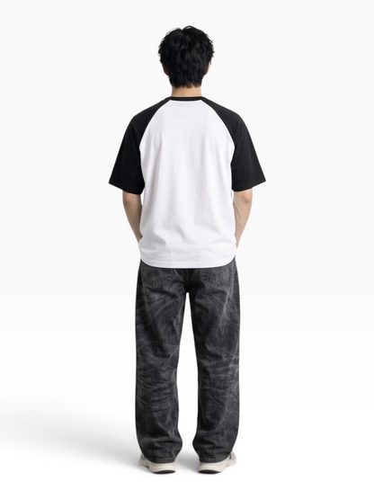 Back view of a person wearing an E7 oversized white and black raglan sleeve cotton t-shirt with dark jeans