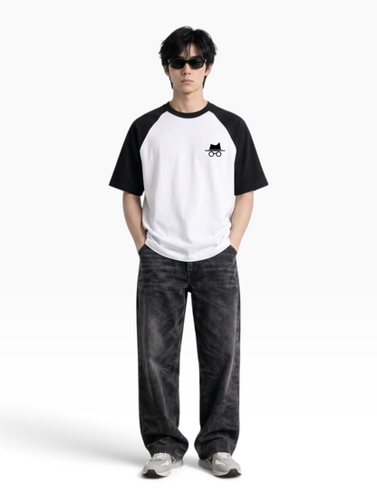 E7 unisex oversized raglan t-shirt in white and black cotton with a small logo on the chest worn by a male model.