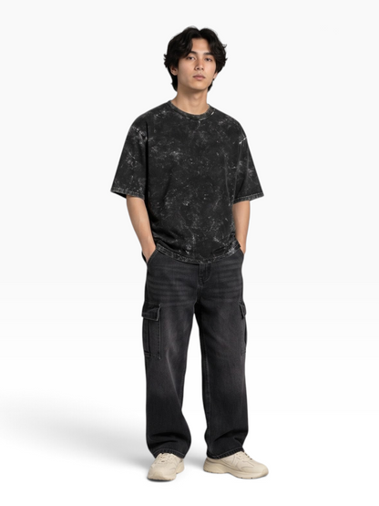 E7 unisex oversized t-shirt in black acid-washed cotton worn by a model with dark cargo pants and sneakers
