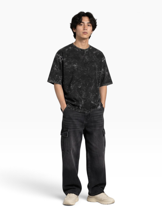 E7 unisex oversized t-shirt in black acid-washed cotton worn by a model with dark cargo pants and sneakers